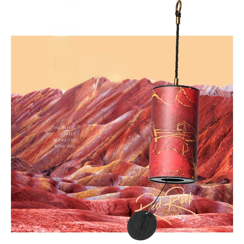 Decorative wind bell with red and gold design against a mountainous landscape background