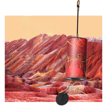 Decorative wind bell with red and gold design against a mountainous landscape background
