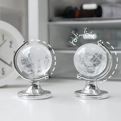 Two small globe models on a white surface with a blurred background