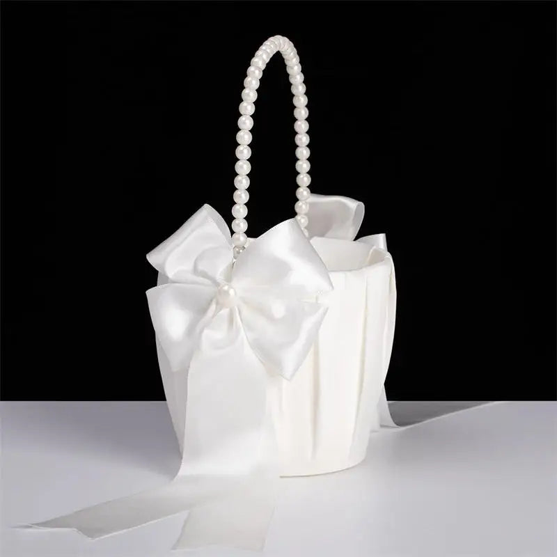 White handbag with pearl handle and large bow on a black background
