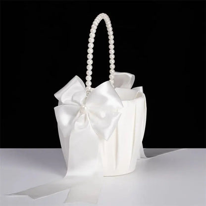 White handbag with pearl handle and large bow on a black background