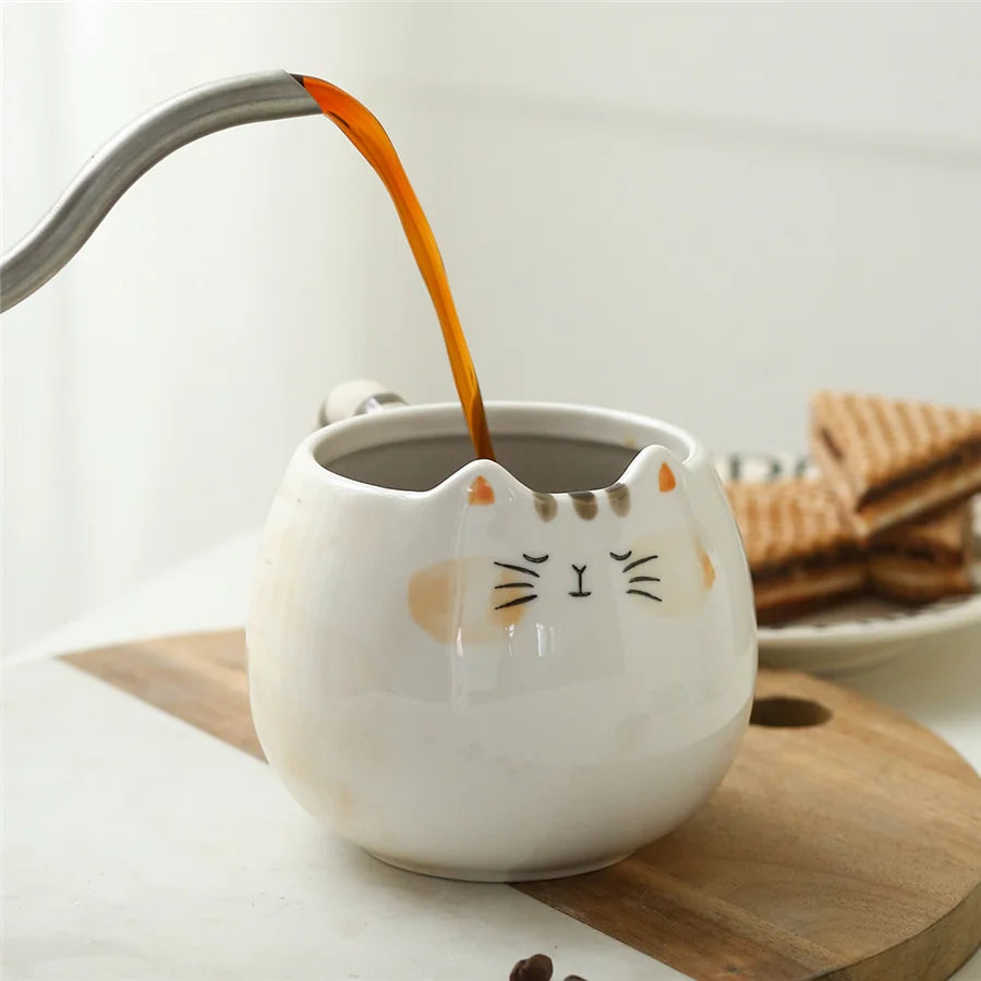 Cat-shaped mug with coffee being poured into it on a wooden coaster.
