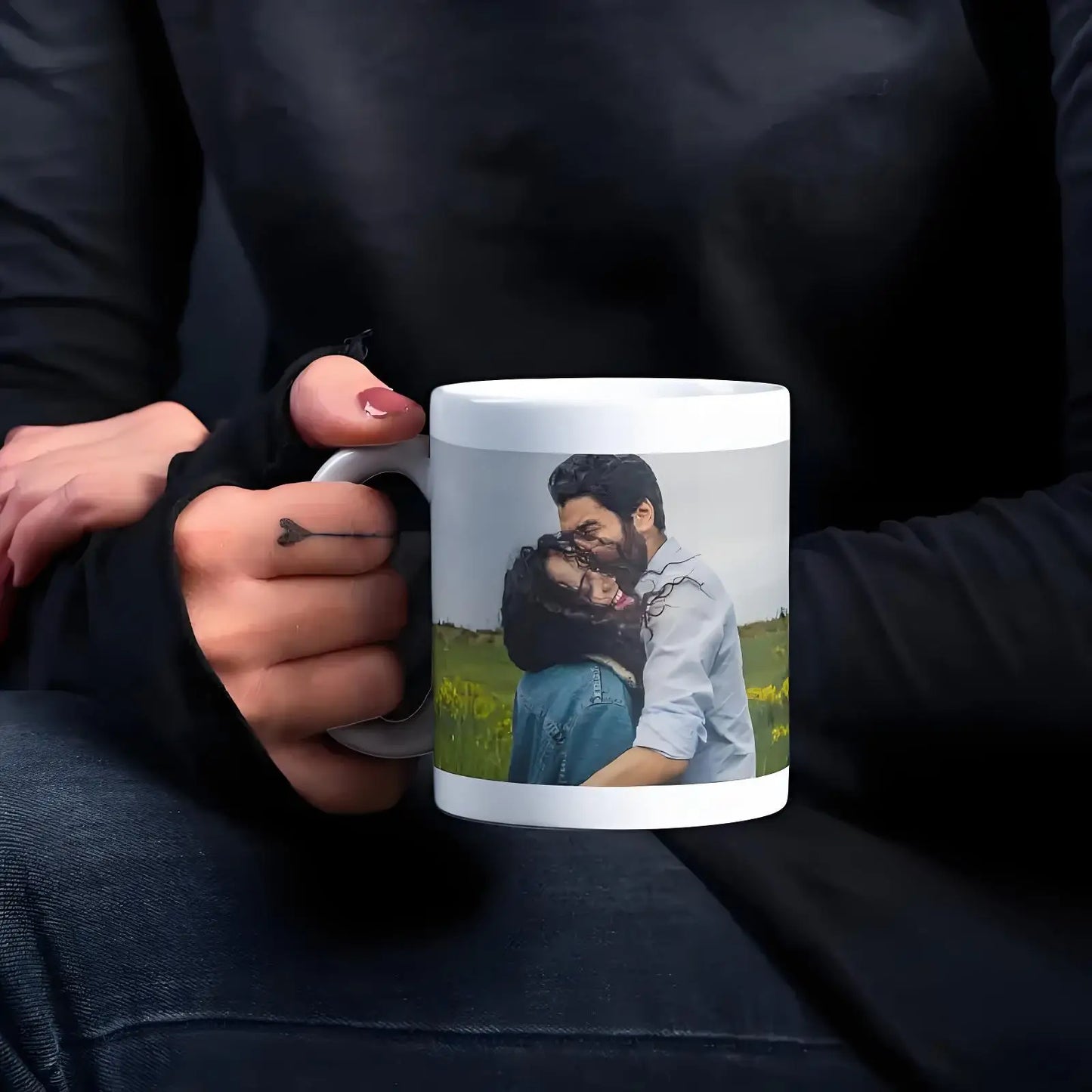 Person holding a mug with a printed photo of two people embracing outdoors.