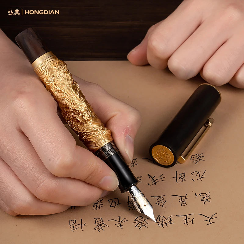 Hand holding a gold and black fountain pen with a close-up of the pen tip on a beige background.