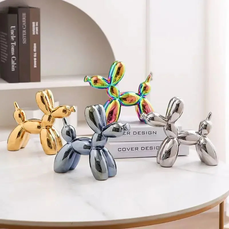 Metallic balloon dog sculptures in gold, silver, and rainbow colors on a white surface.