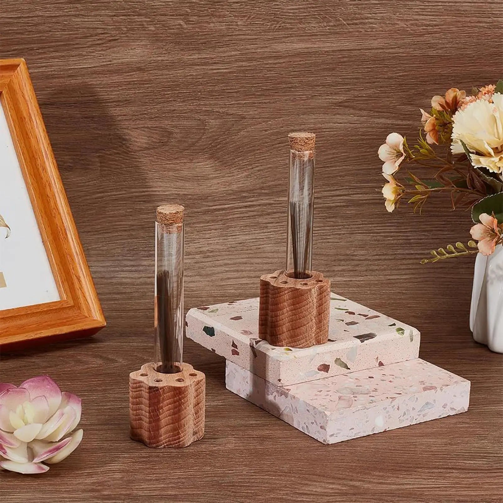 Wooden desk organizer with cylindrical items on a wooden surface with flowers and a picture frame.