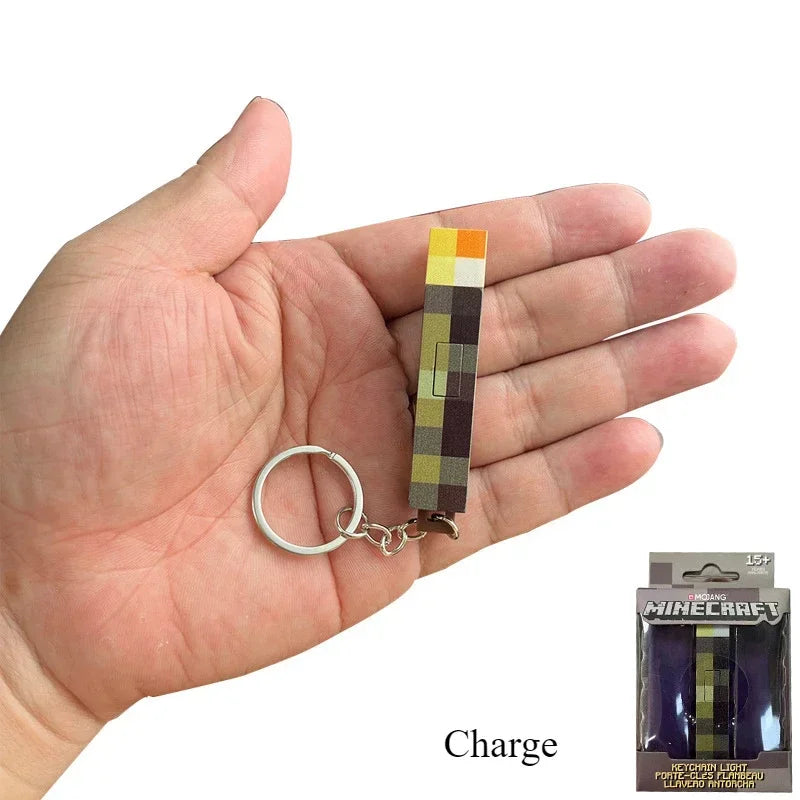 Hand holding a Minecraft-themed keychain with a pixelated design, next to its packaging.