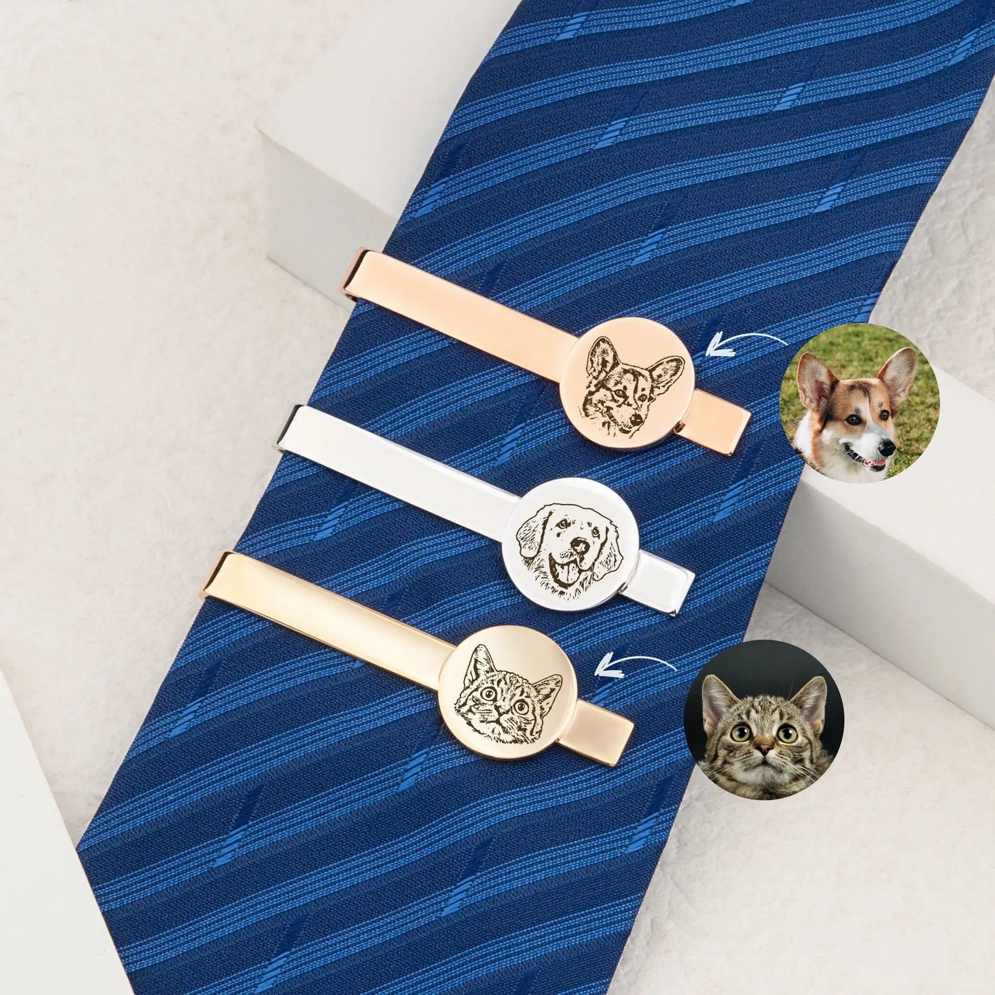 Three tie clips with dog and cat designs on a blue tie.