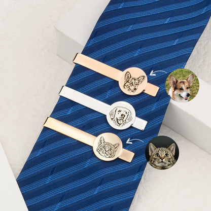 Three tie clips with dog and cat designs on a blue tie.