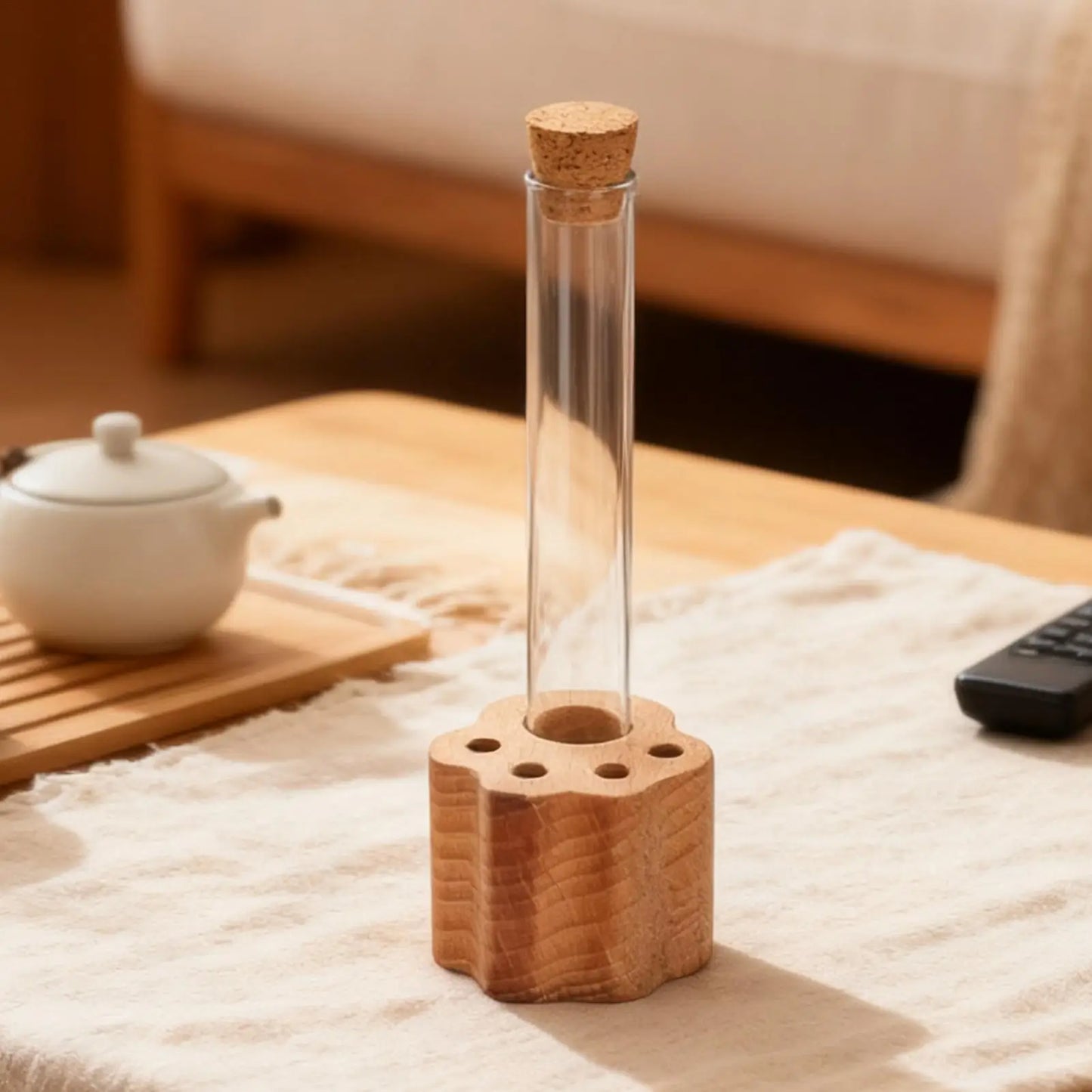 Clear glass bottle with cork lid on a wooden base on a table.