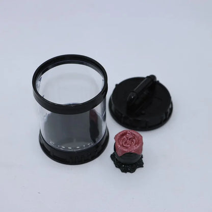 Clear cylindrical container with black lid and decorative rose on a white background