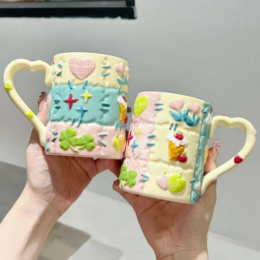 Two colorful ceramic mugs with decorative patterns held by a person.