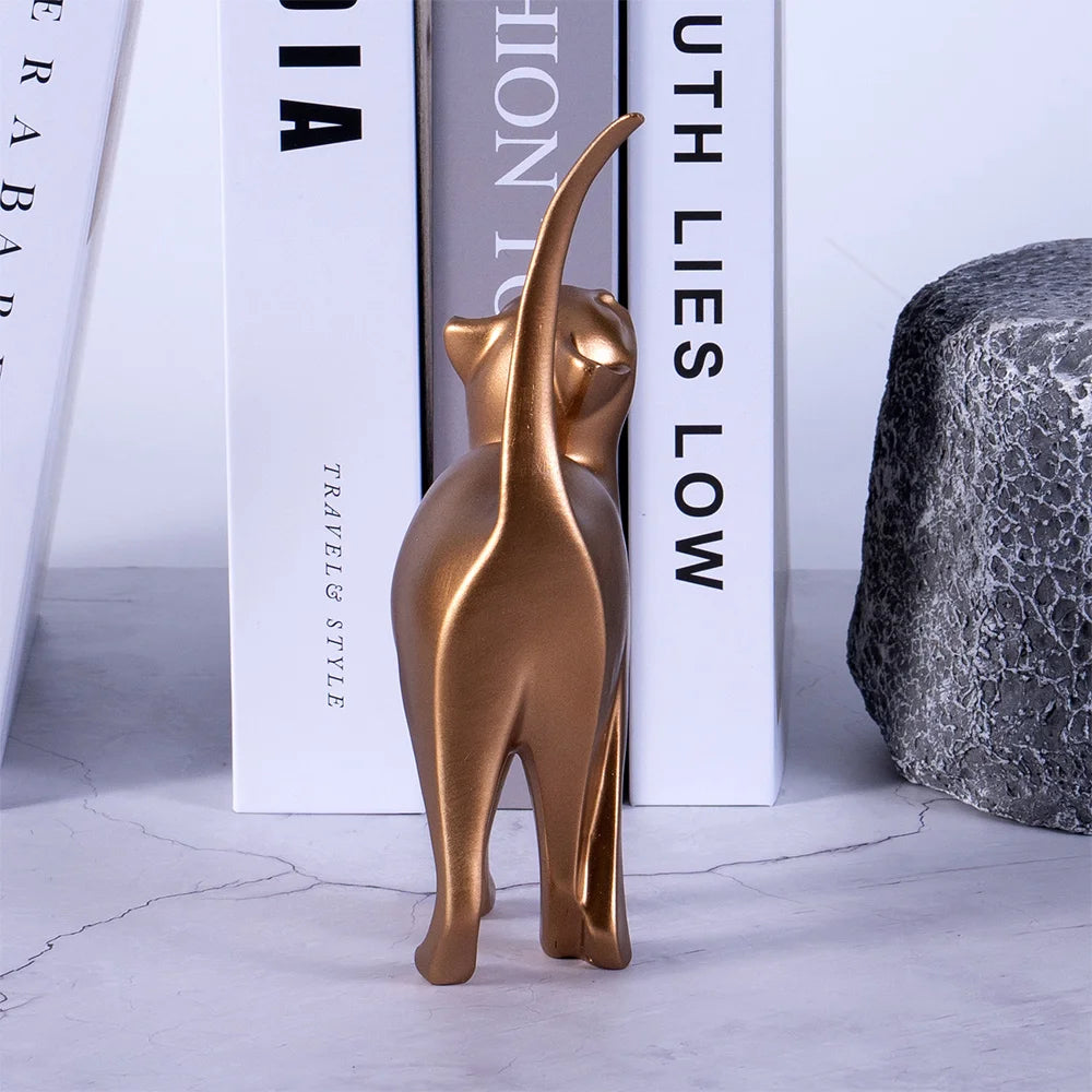 Bronze cat figurine on a white surface with books in the background