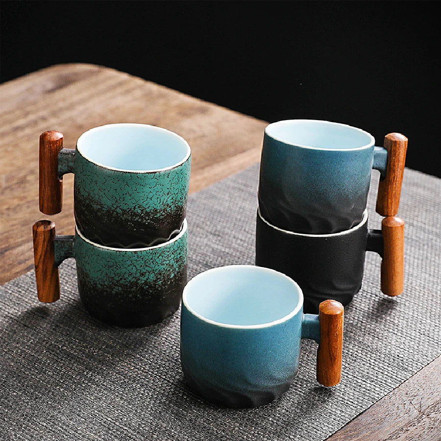 Set of ceramic mugs with wooden handles on a textured surface