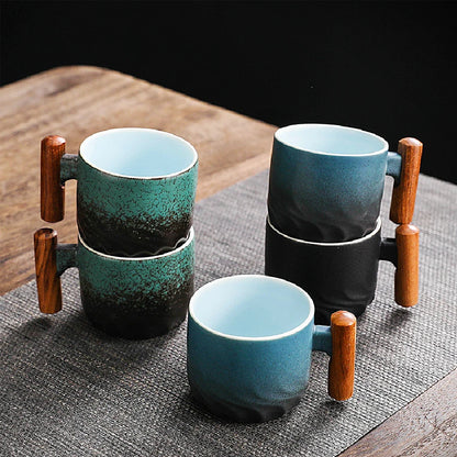 Set of ceramic mugs with wooden handles on a textured surface