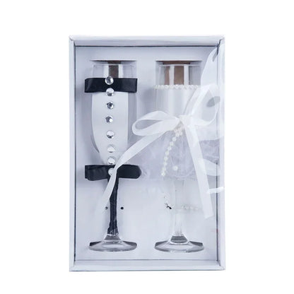 Two decorative glasses with black bases and white ribbons in a white box on a white background
