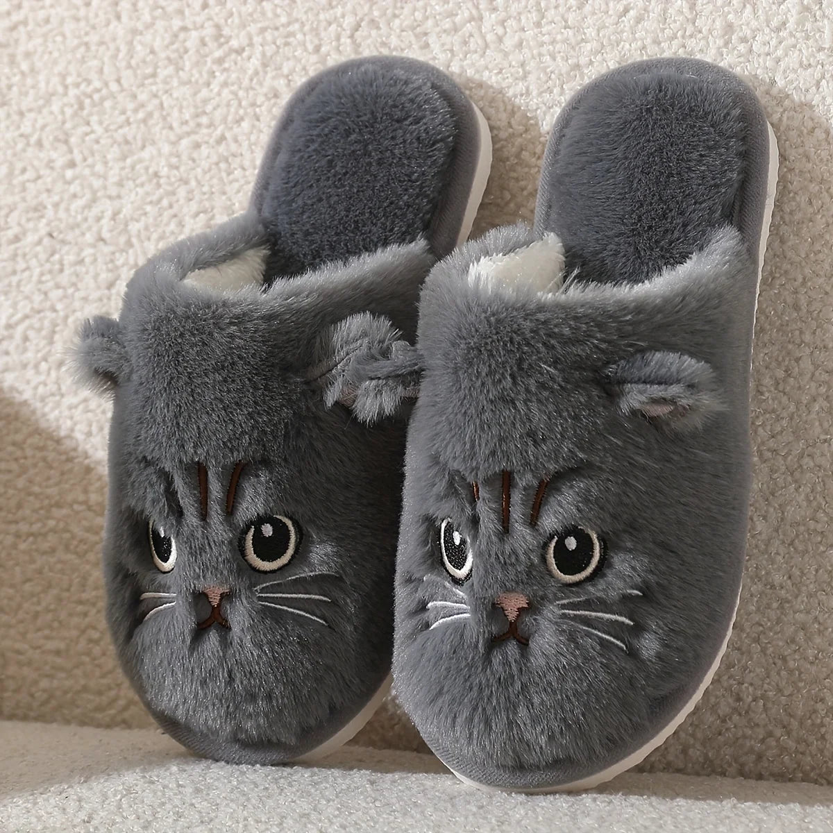 Gray cat-shaped slippers on a textured surface