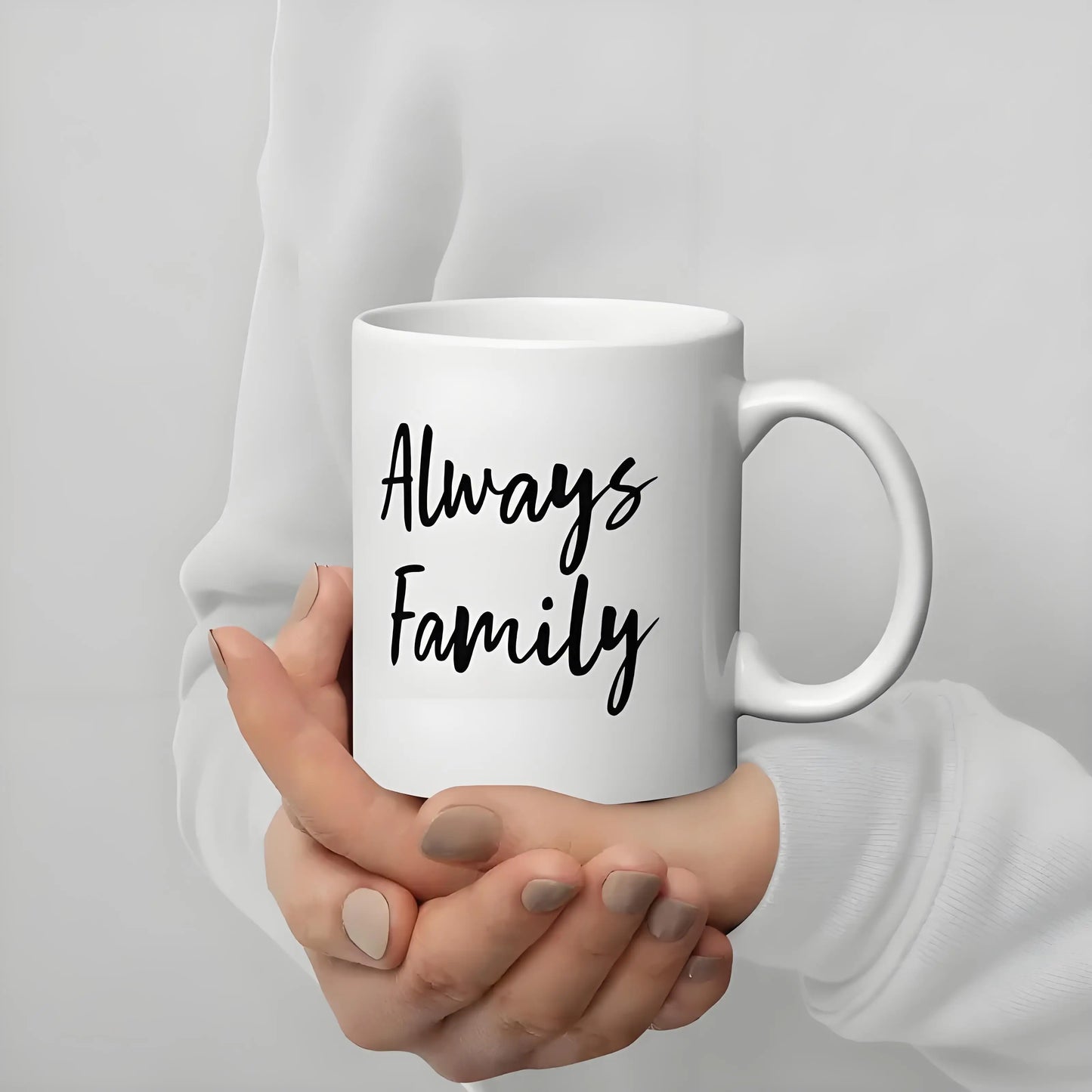 White mug with 'Always Family' text held by a person against a plain background