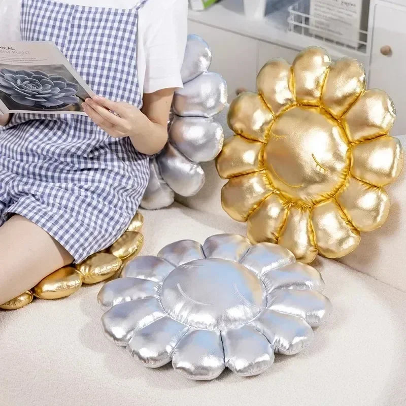 Gold and silver flower-shaped cushions on a light-colored floor with a person reading a book.