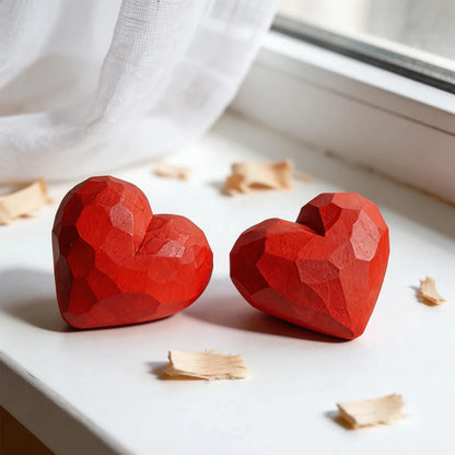 Two red geometric heart-shaped objects on a white surface with a light background