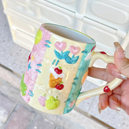 Colorful ceramic mug with floral designs held by a hand on a light background