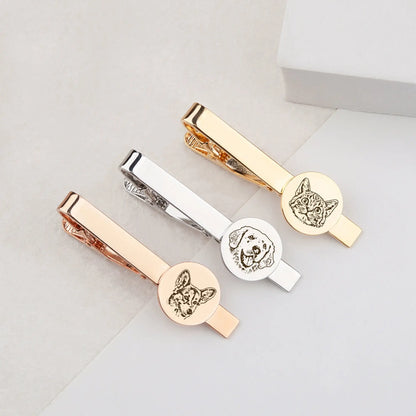 Three gold, silver, and rose gold tie clips with engraved dog designs on a light gray background.