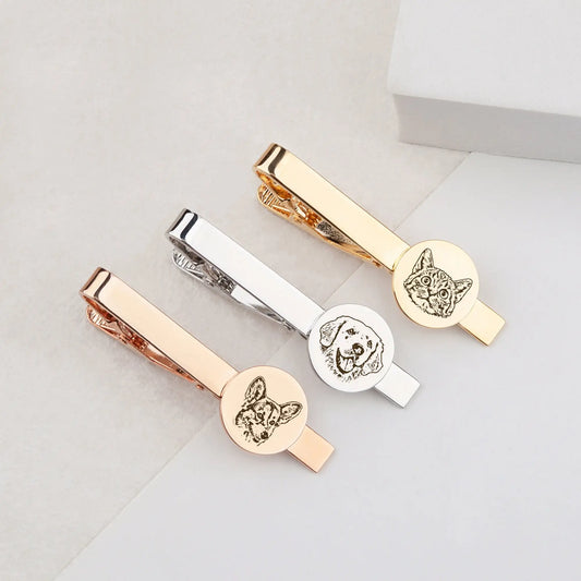 Three gold, silver, and rose gold tie clips with engraved dog designs on a light gray background.