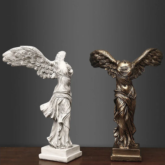 Two statues of winged figures, one silver and one bronze, on a dark background.
