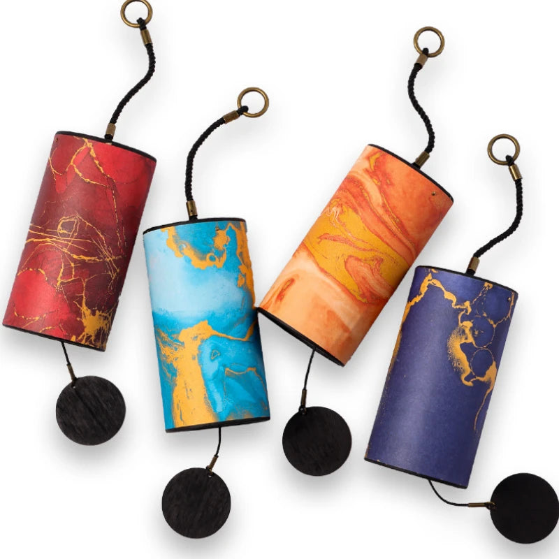 Four colorful cylindrical cat toys with string and black pom-poms on a white background