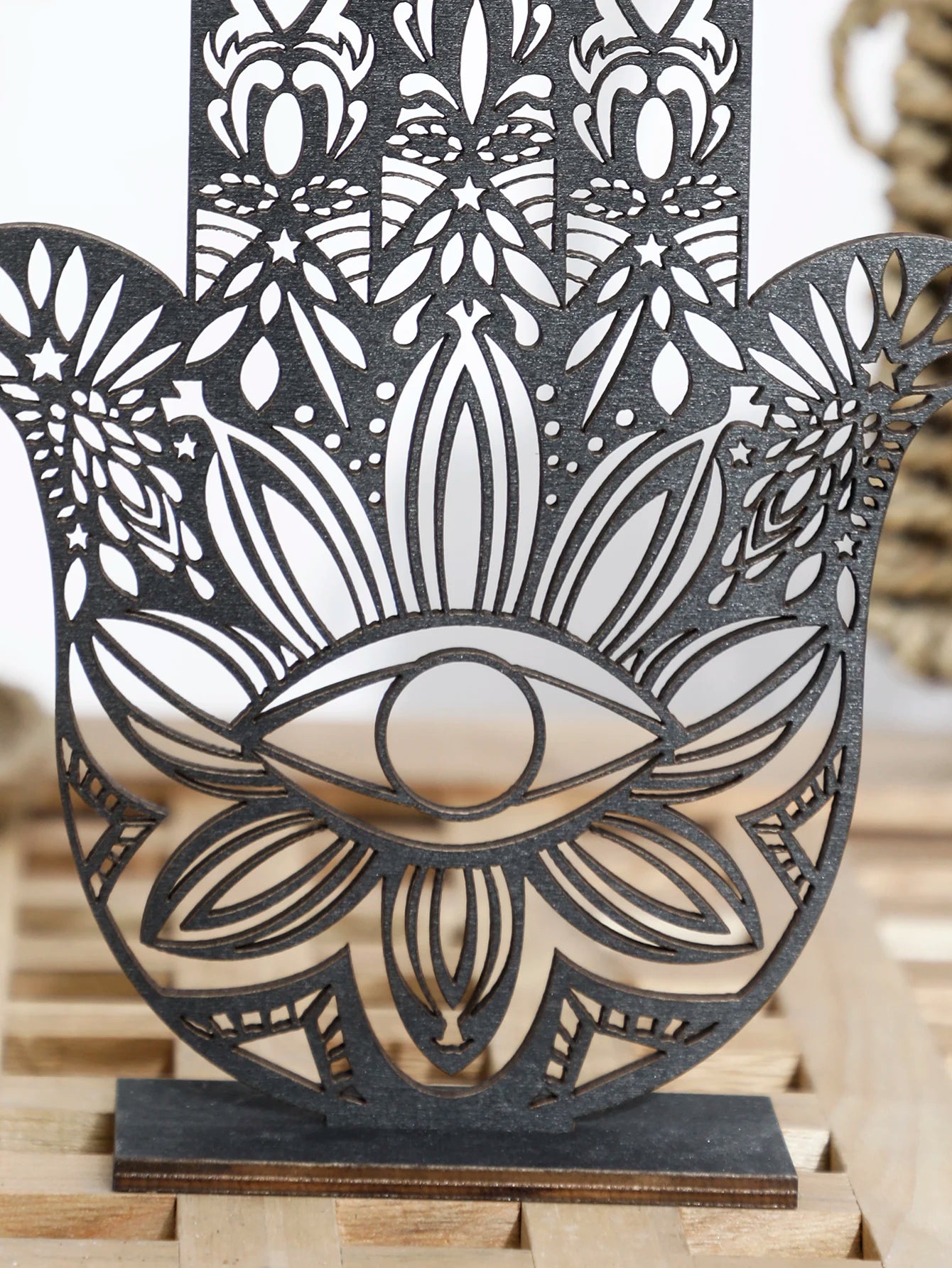Decorative metal wall art with intricate patterns and an eye design on a wooden surface.