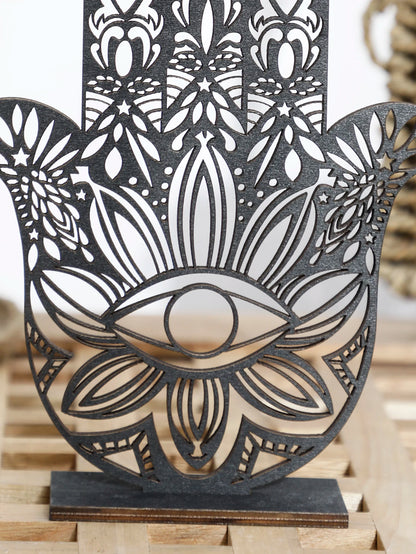 Decorative metal wall art with intricate patterns and an eye design on a wooden surface.