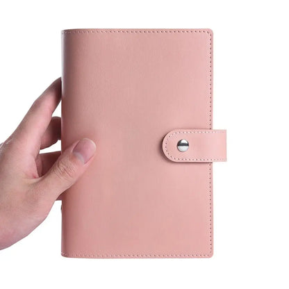 Pink leather planner held by a hand on a white background