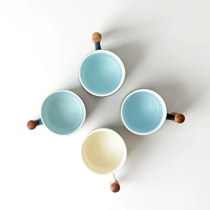Set of four ceramic bowls with wooden handles on a white background