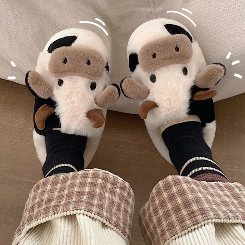 Pair of cartoon cow slippers worn indoors on a wooden floor.