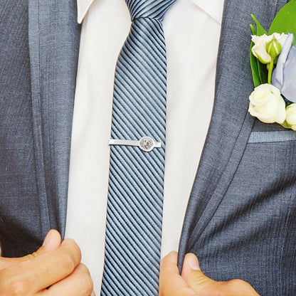 Close-up of a person wearing a gray suit with a white shirt, blue striped tie, and a boutonniere.