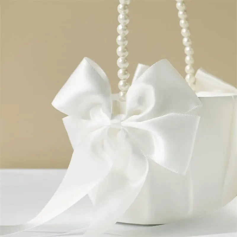 White gift bag with a large bow and pearl handle on a beige background