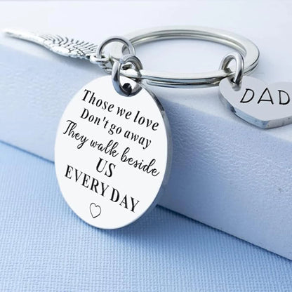 Silver keychain with engraved message on a light blue background