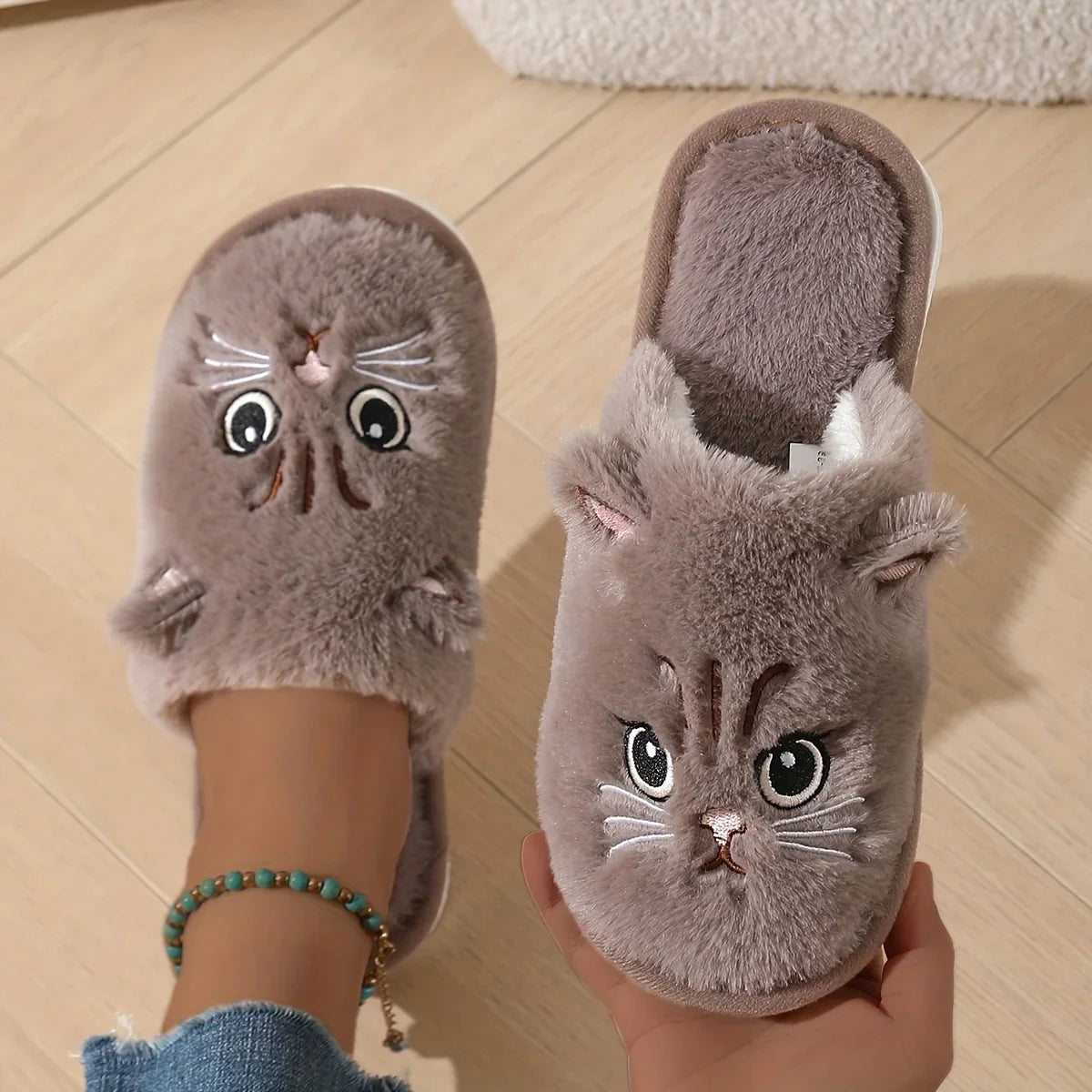 Cat-shaped slippers worn by a person on a wooden floor