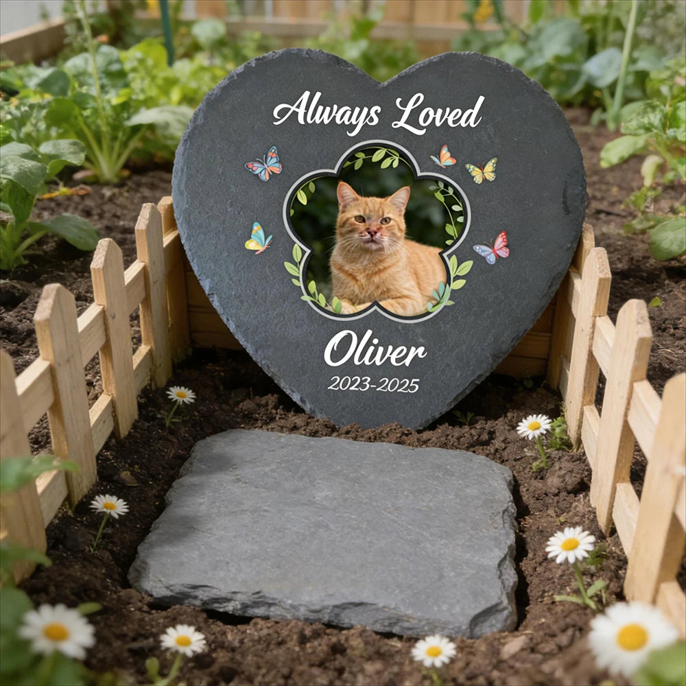 Heart-shaped slate with a cat's photo and 'Always Loved Oliver' text in a garden setting.