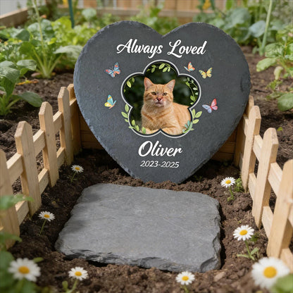 Heart-shaped slate with a cat's photo and 'Always Loved Oliver' text in a garden setting.