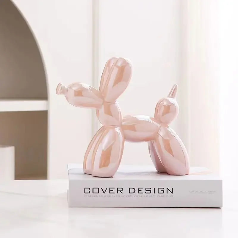 Pink balloon dog sculpture on a book with a minimal background
