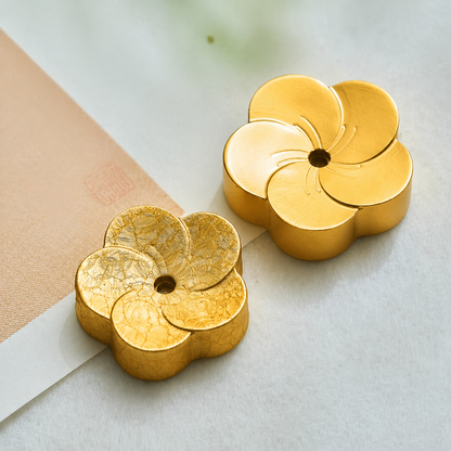 Two gold flower-shaped objects on a light background